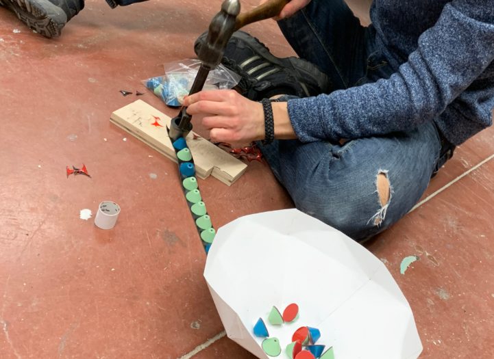 Setting colored spacers onto a rod with a mallet